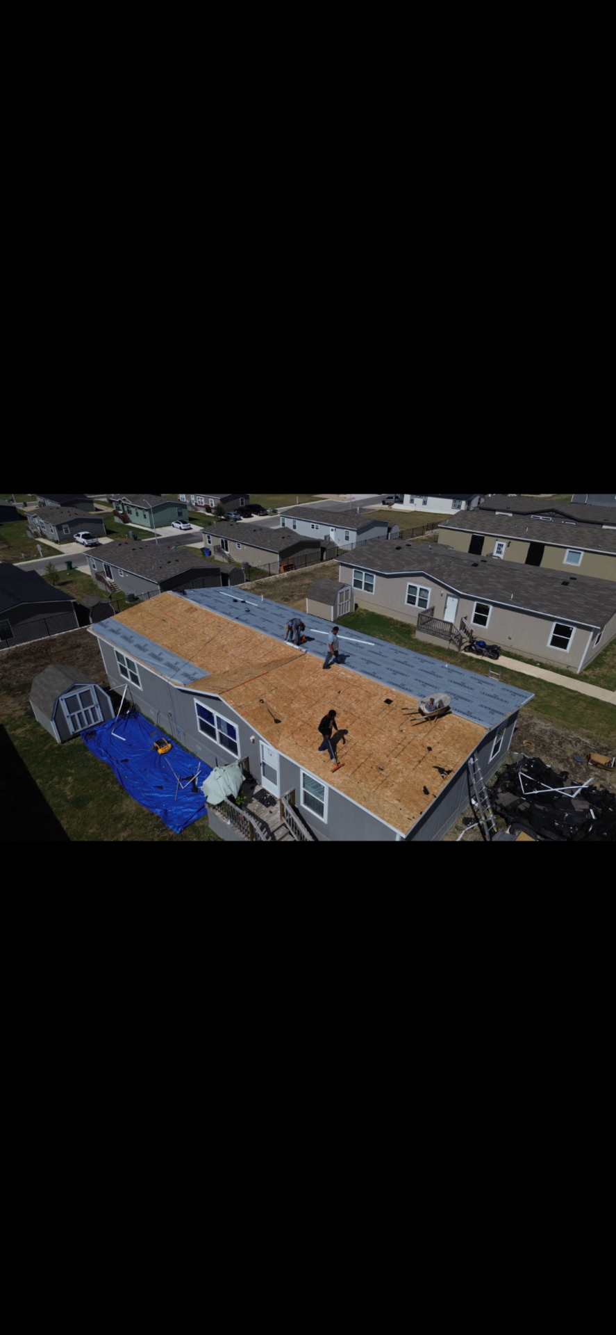 Aerial before photo of a Kyle, TX home with the old roof torn off, exposed OSB decking, and crew prepping for new underlayment.